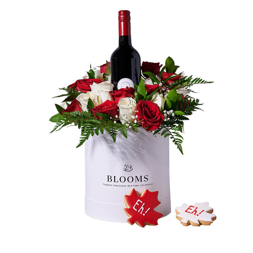 Touch of Canada Gift, sharing bottle of wine, two Canada Day maple leaf cookies, and a stunning floral arrangement with red and white roses presented in a large hat box, Gift Sets from Canada Blooms- Same Day Canada Delivery.