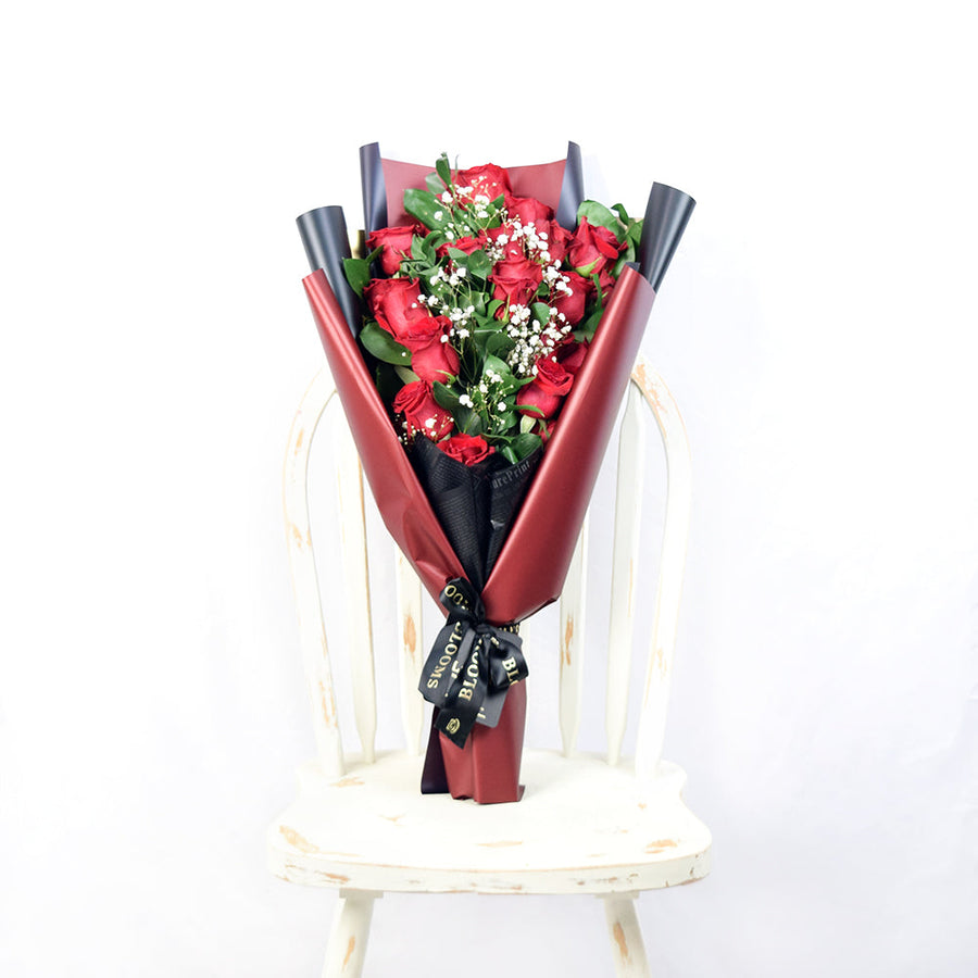 This bouquet includes a selection of deep red roses, baby’s breath, and ruscus gathered in floral wrap with designer ribbon. Blooms Canada Delivery